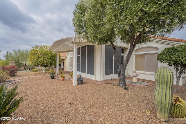 view of home's exterior with a pergola and a sunroom