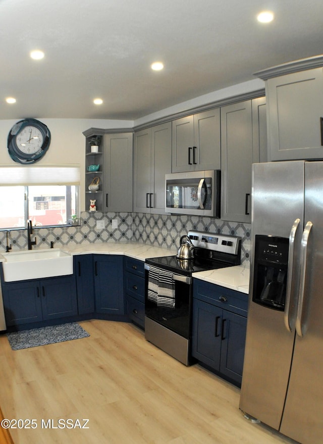 449 W San Ignacio, Green Valley, AZ 85614 - kitchen featuring stainless steel appliances, a sink, open shelves, light wood-type flooring, and backsplash