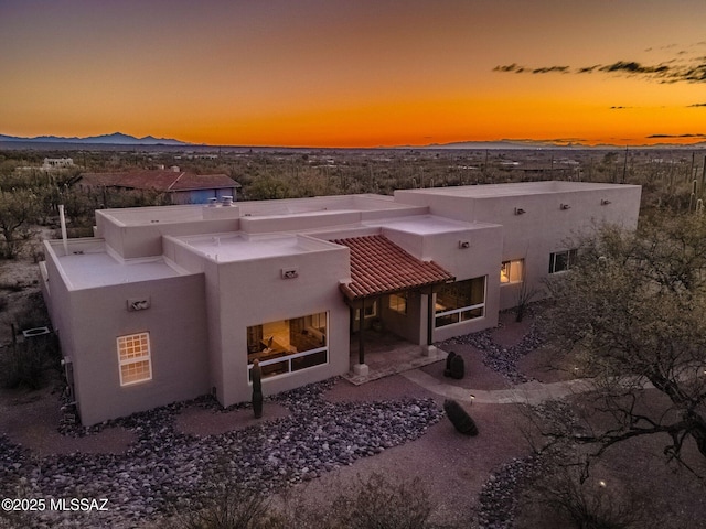 back of property with a patio, a mountain view, and stucco siding