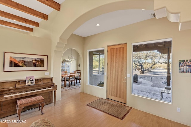 entryway featuring a chandelier, beam ceiling, and light hardwood / wood-style floors