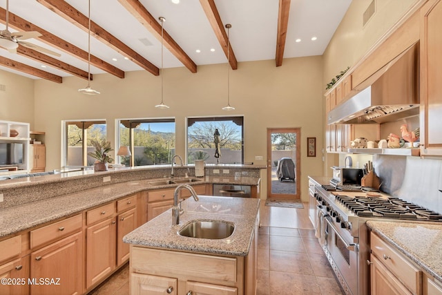 kitchen with sink, light brown cabinets, double oven range, an island with sink, and pendant lighting