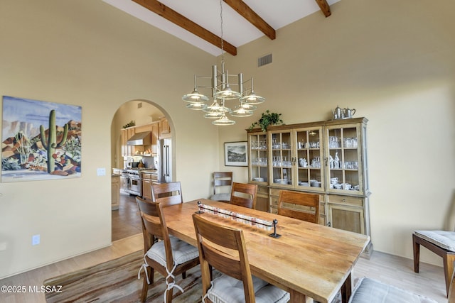 dining area with an inviting chandelier, high vaulted ceiling, beamed ceiling, and light wood-type flooring