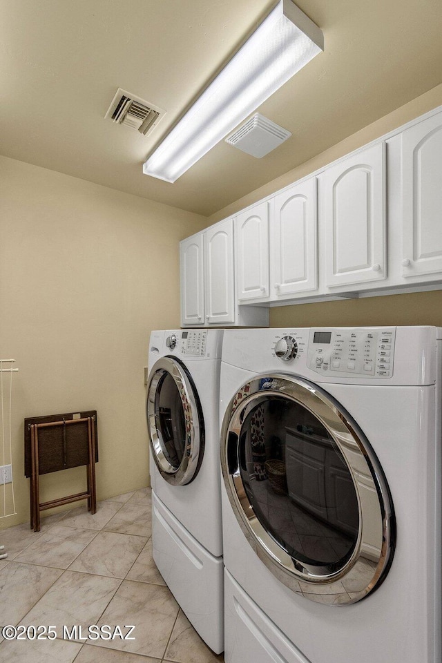 clothes washing area with cabinets and washer and dryer