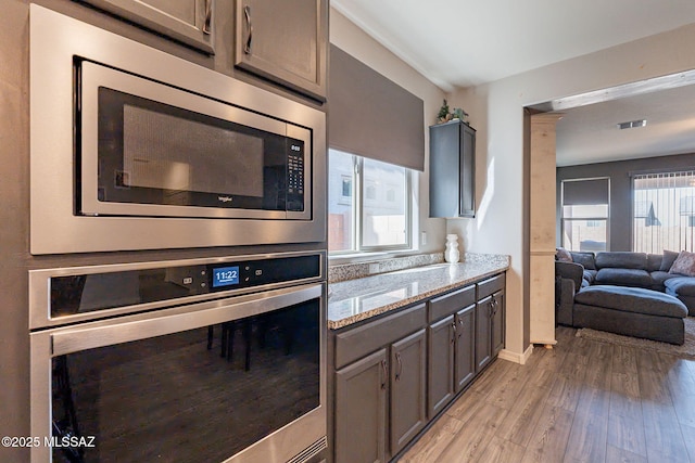 kitchen with stainless steel appliances, light stone countertops, and light hardwood / wood-style floors