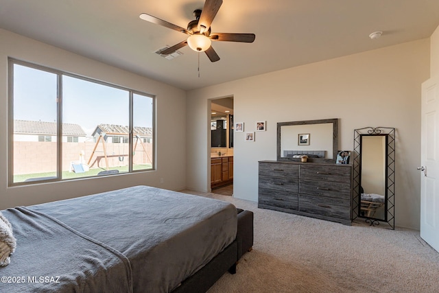 bedroom with connected bathroom, light colored carpet, and ceiling fan