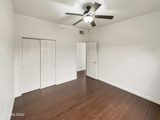 unfurnished bedroom featuring dark hardwood / wood-style flooring, ceiling fan, and a closet