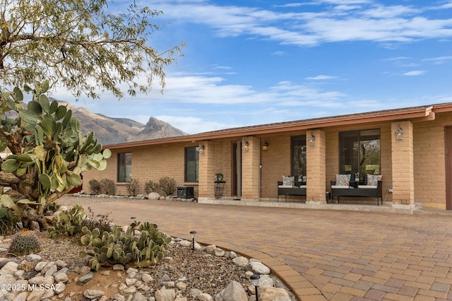 back of property featuring central AC unit, outdoor lounge area, a mountain view, and a patio area