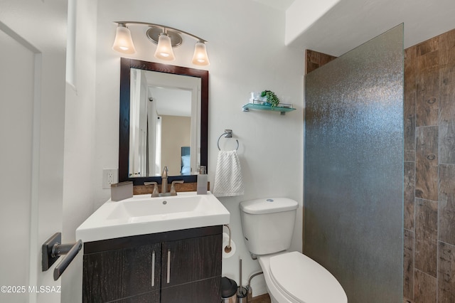 bathroom with vanity, toilet, and a tile shower