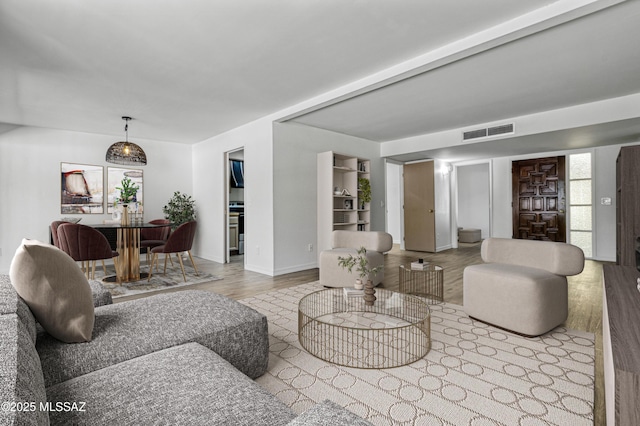 living area with visible vents, baseboards, and wood finished floors