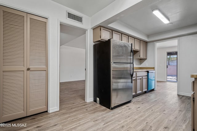 kitchen with freestanding refrigerator, light wood-type flooring, visible vents, dishwasher, and light countertops