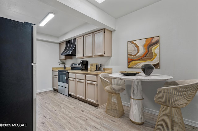 kitchen featuring baseboards, wall chimney range hood, light countertops, light wood-type flooring, and appliances with stainless steel finishes