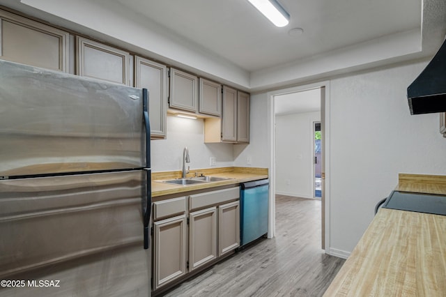 kitchen with dishwasher, a sink, freestanding refrigerator, light wood finished floors, and extractor fan