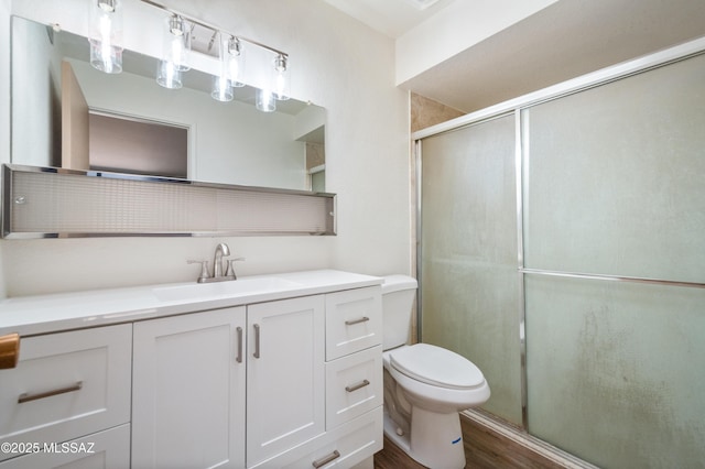 bathroom featuring toilet, a stall shower, wood finished floors, and vanity