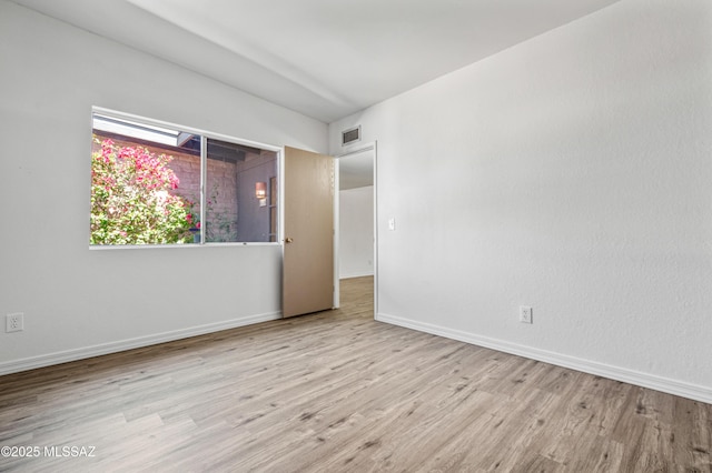spare room featuring visible vents, baseboards, and wood finished floors