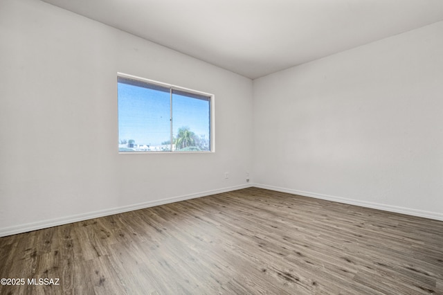 spare room featuring baseboards and wood finished floors