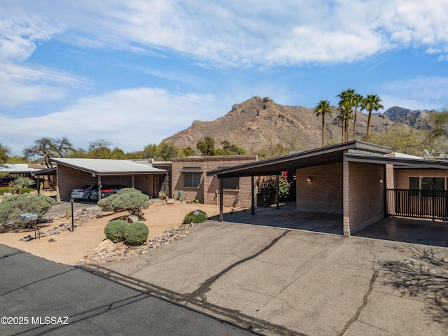 mid-century inspired home with a carport, a mountain view, brick siding, and aphalt driveway