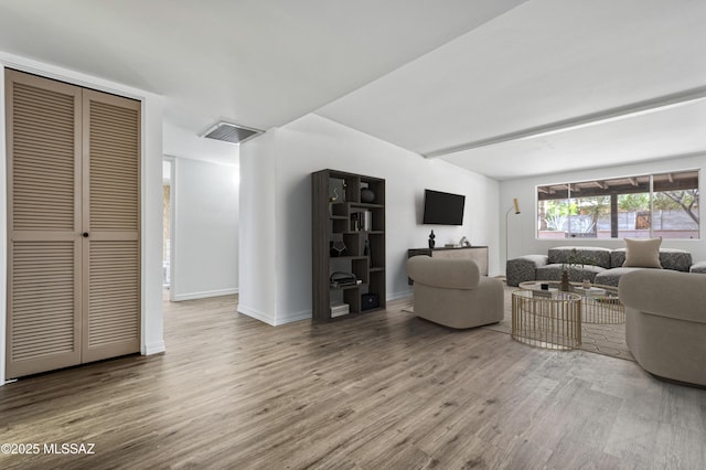 living room featuring visible vents, baseboards, and wood finished floors