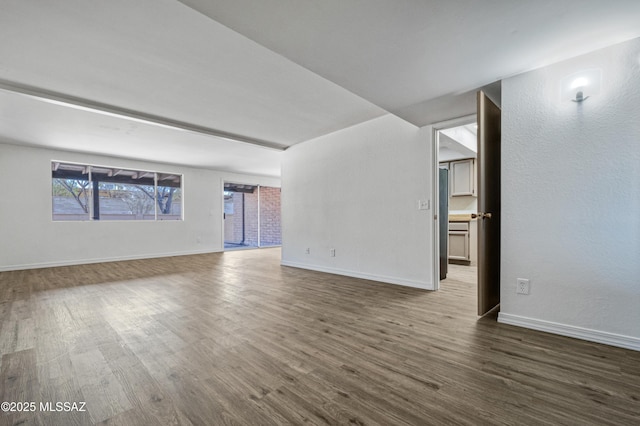 spare room with baseboards and dark wood finished floors