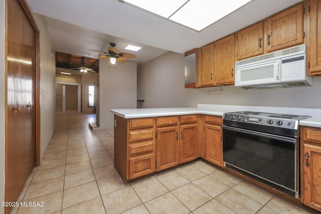 kitchen featuring ceiling fan, electric range, a skylight, light tile patterned flooring, and kitchen peninsula