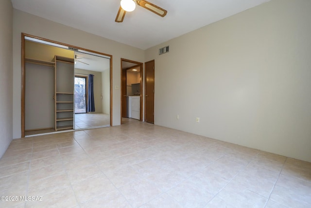 unfurnished bedroom with washer / clothes dryer, light tile patterned floors, a closet, and ceiling fan