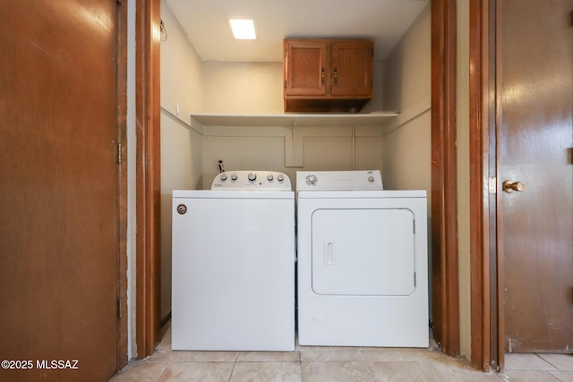 laundry area featuring cabinets, light tile patterned floors, and washing machine and clothes dryer