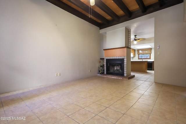 unfurnished living room with ceiling fan, beam ceiling, a fireplace, light tile patterned flooring, and wooden ceiling