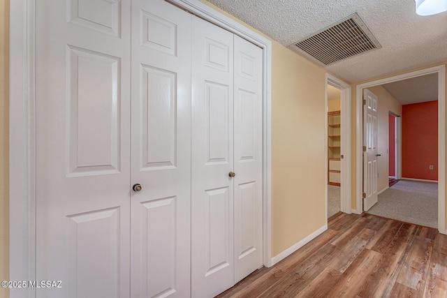 corridor featuring wood-type flooring and a textured ceiling