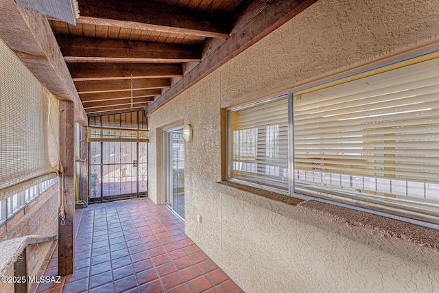 unfurnished sunroom featuring beamed ceiling and wooden ceiling