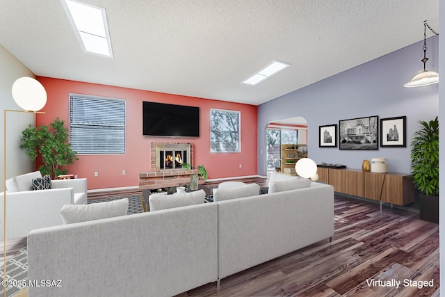 living room with vaulted ceiling, a brick fireplace, dark hardwood / wood-style floors, and a textured ceiling