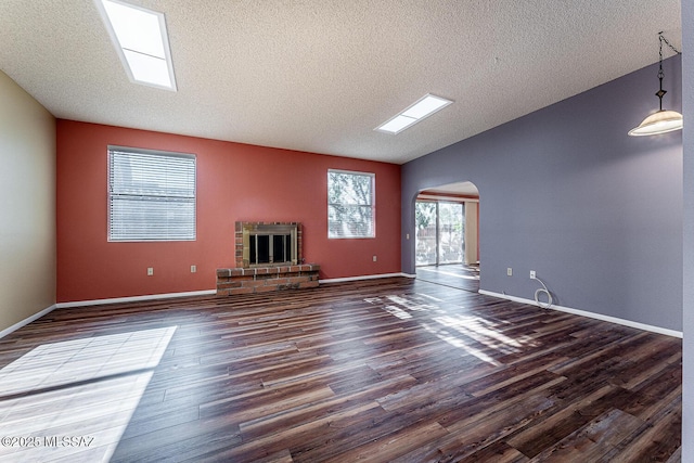 unfurnished living room featuring a fireplace, dark wood-type flooring, vaulted ceiling, and a textured ceiling