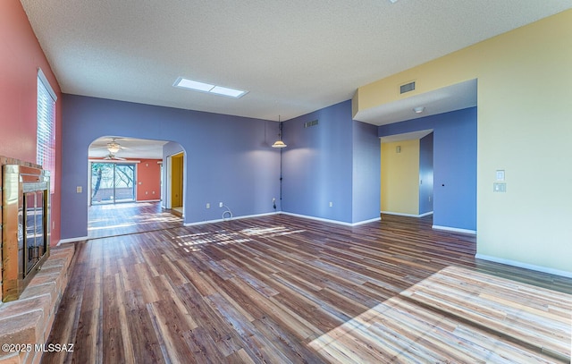 unfurnished living room with wood-type flooring, a brick fireplace, and a textured ceiling