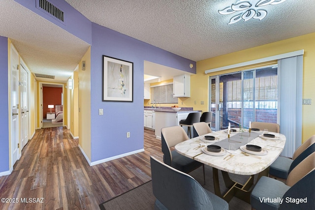 dining area featuring dark wood-type flooring and a textured ceiling