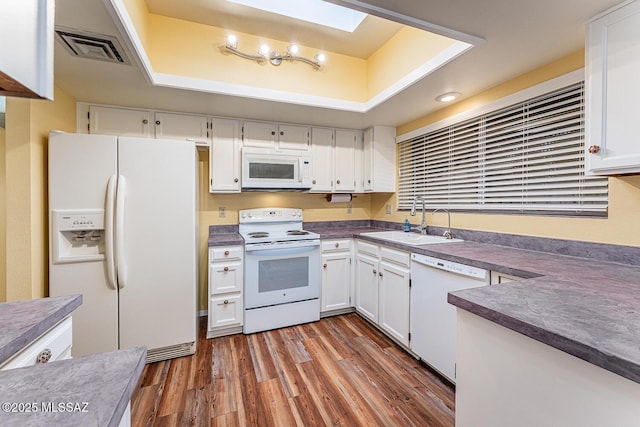 kitchen featuring sink, white cabinetry, dark hardwood / wood-style flooring, a raised ceiling, and white appliances