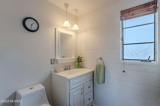 bathroom featuring vanity, brick wall, a wealth of natural light, and toilet