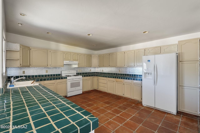 kitchen featuring sink, tile counters, white appliances, and decorative backsplash