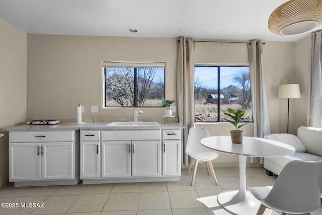 kitchen with white cabinetry, sink, a wealth of natural light, and light tile patterned floors