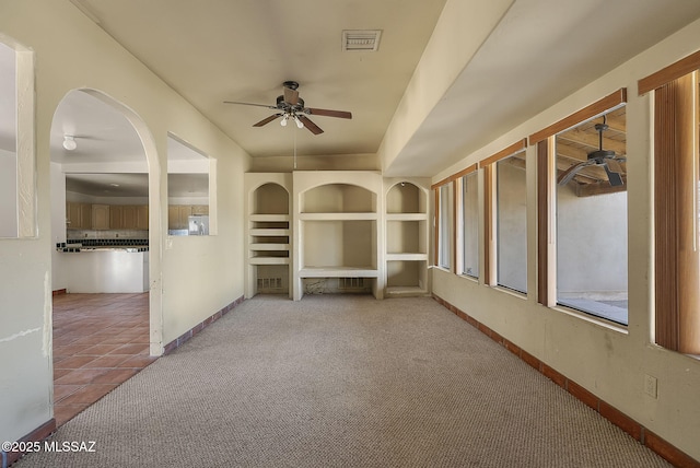 unfurnished living room featuring ceiling fan, light colored carpet, and built in features