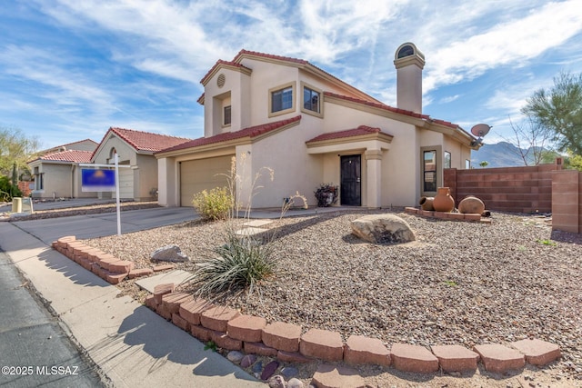 mediterranean / spanish-style home featuring driveway, an attached garage, fence, and a tiled roof