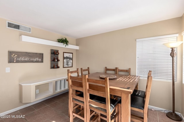 dining room featuring dark tile patterned floors, visible vents, and baseboards