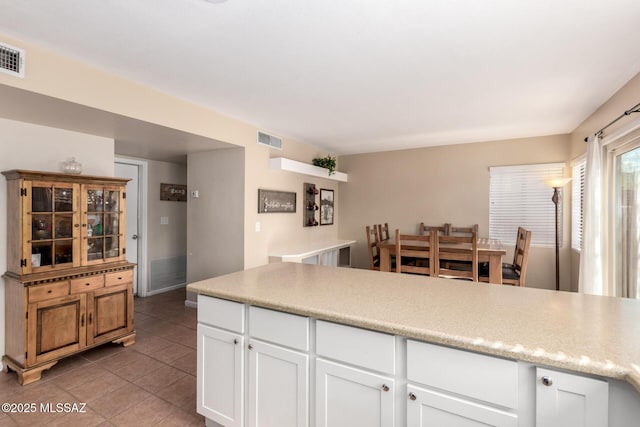 kitchen with white cabinets, dark tile patterned floors, visible vents, and light countertops