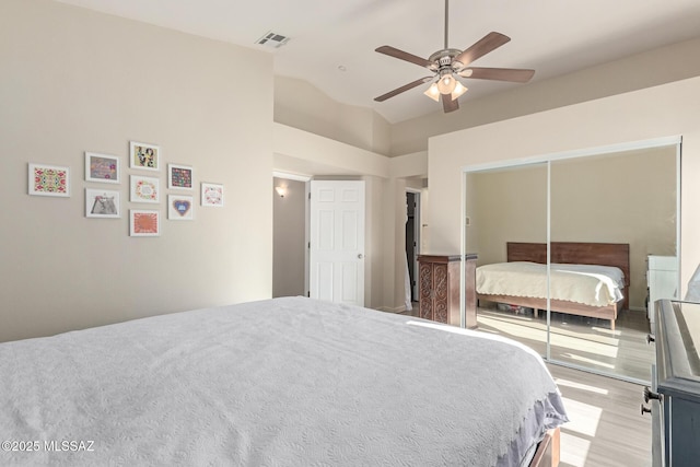 bedroom with a closet, visible vents, a ceiling fan, vaulted ceiling, and light wood-type flooring