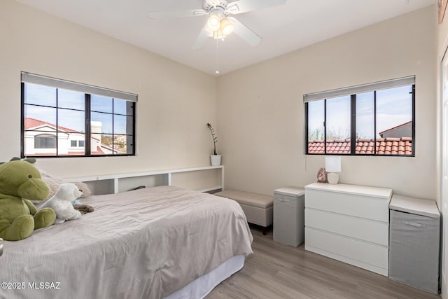 bedroom featuring light wood finished floors, ceiling fan, and multiple windows