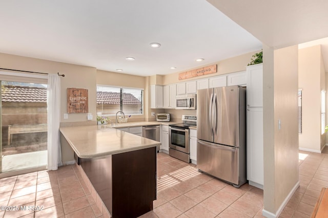 kitchen featuring light tile patterned floors, stainless steel appliances, light countertops, white cabinetry, and a peninsula