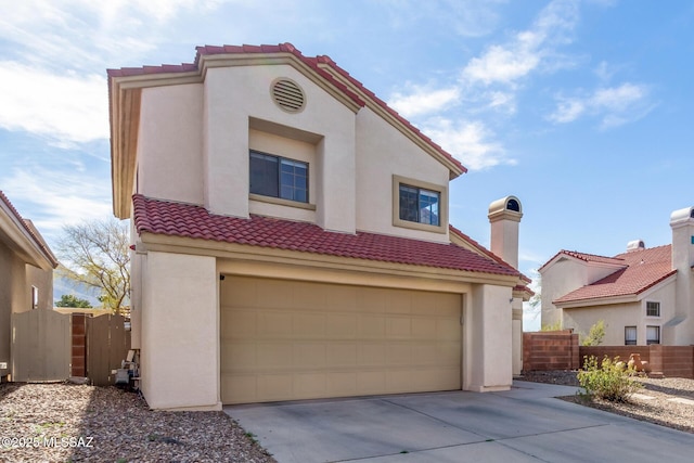 mediterranean / spanish-style house featuring a tiled roof, fence, concrete driveway, and stucco siding