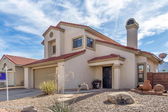 mediterranean / spanish home featuring a tiled roof, driveway, a chimney, and stucco siding