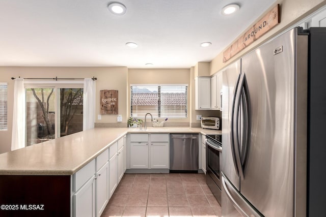 kitchen with light countertops, appliances with stainless steel finishes, plenty of natural light, and white cabinets