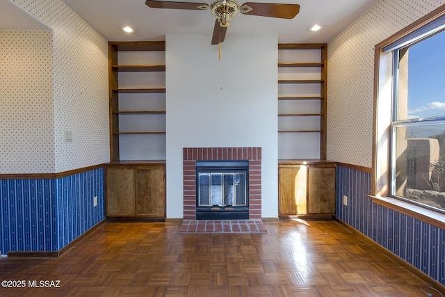 unfurnished living room with built in features, dark parquet floors, and a fireplace