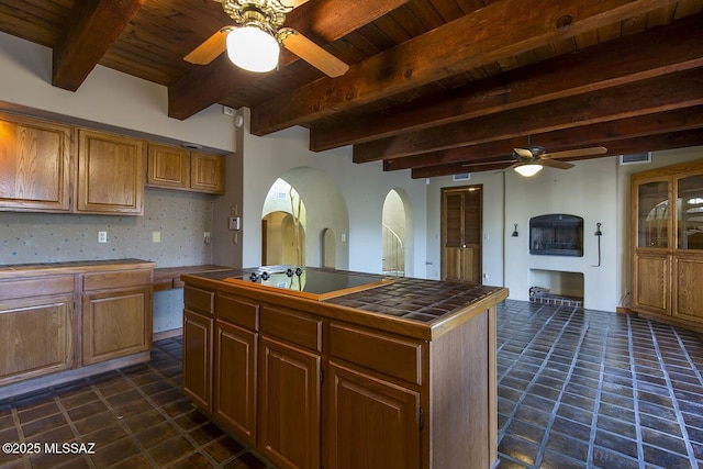 kitchen featuring tile countertops, beam ceiling, wood ceiling, ceiling fan, and black electric stovetop