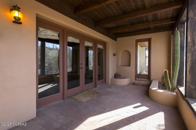 unfurnished living room featuring beamed ceiling, carpet floors, wooden ceiling, and ceiling fan