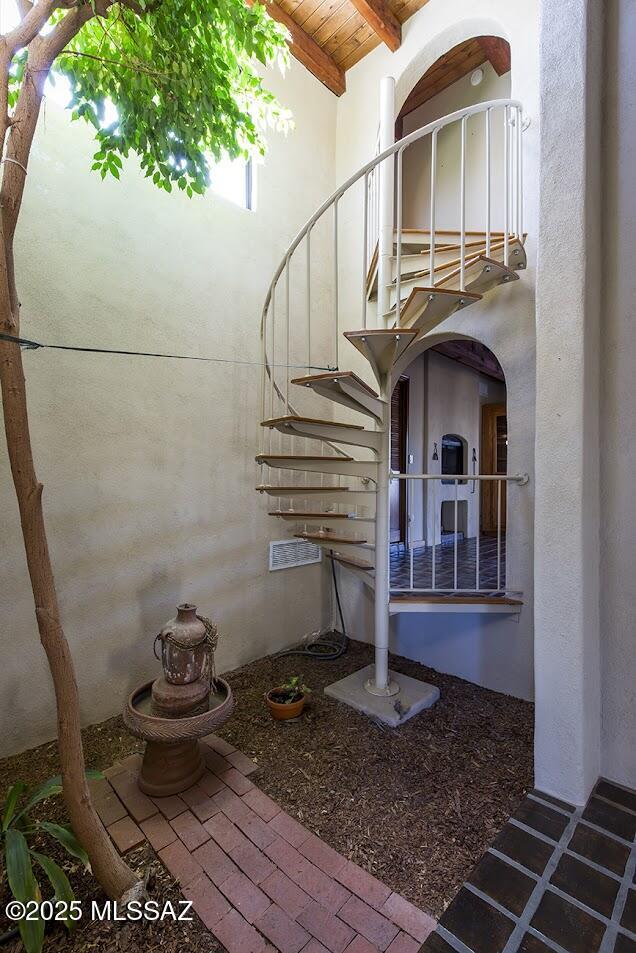 stairs featuring wooden ceiling, beamed ceiling, and a high ceiling